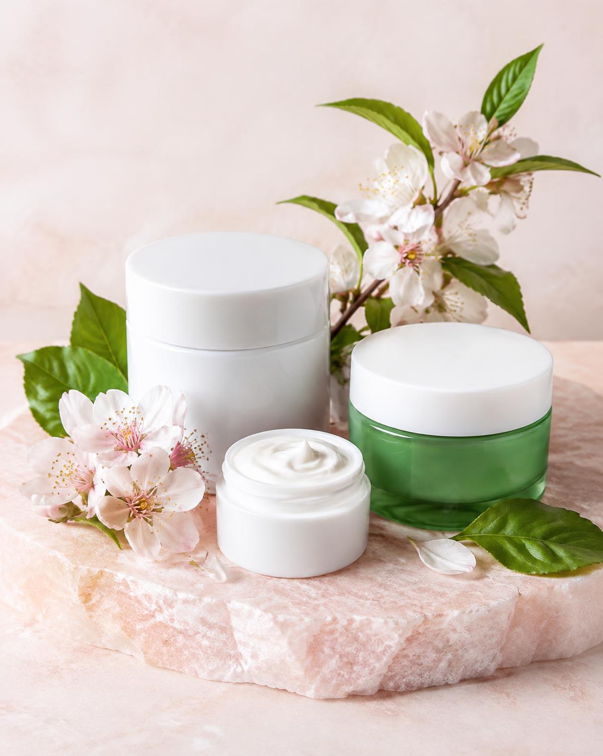 White and green skincare jars with leaves and blossom