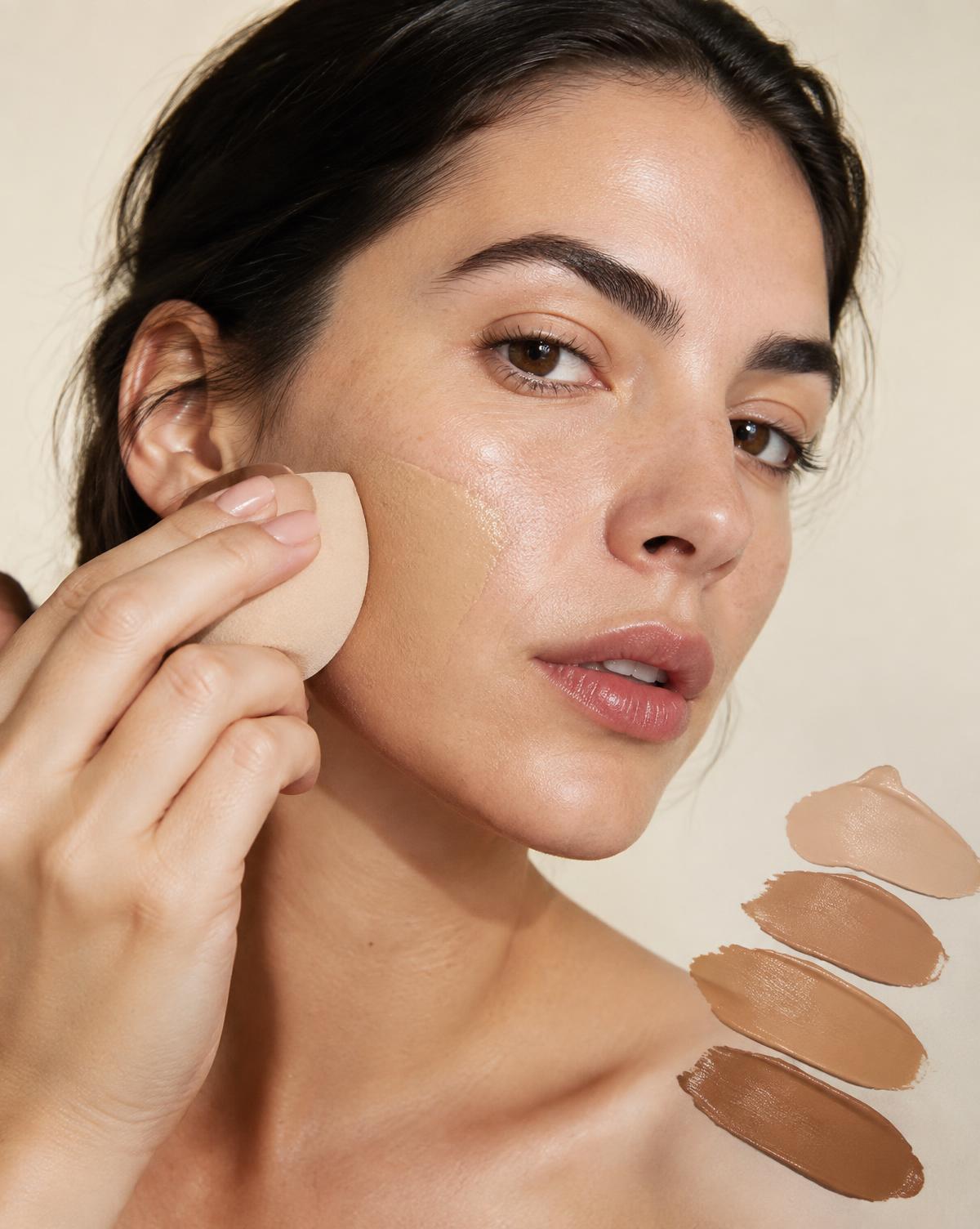 Woman blending foundation with a beauty sponge
