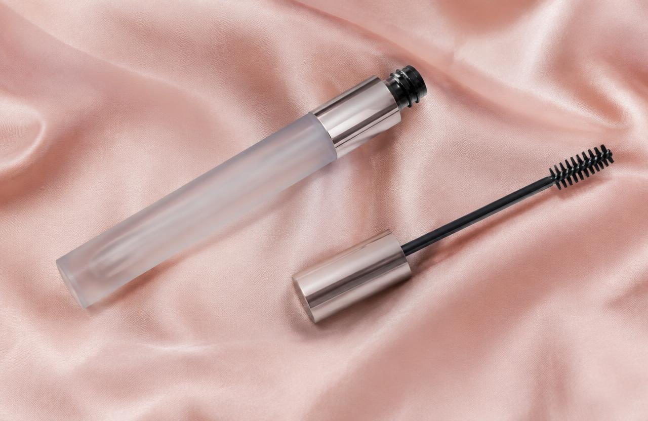 Lash serum tube and spoolie on pink silk